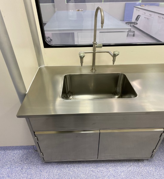 Real laboratory sink wall with stainless steel basin and cleanable wet-area wall interface